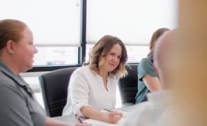 Confident female employee engaging in a collaborative team meeting at Glassical Designs, a woman-owned corporate recognition company focused on fostering workplace growth and support.