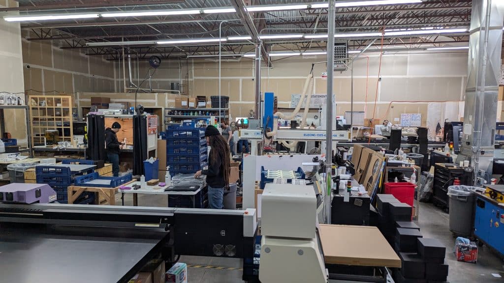 Image shows a warehouse with several machines and people making awards